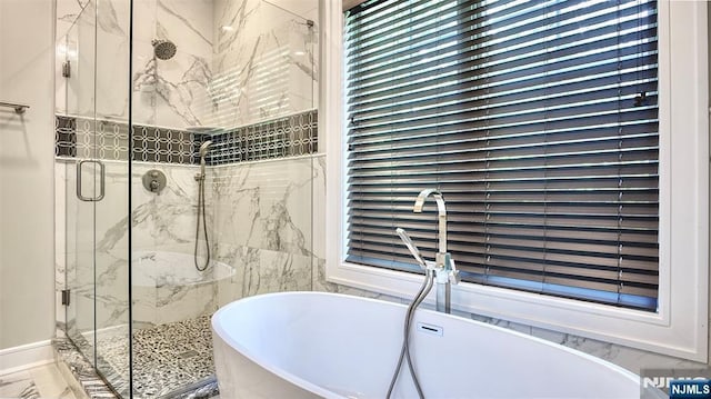 full bath with marble finish floors, a marble finish shower, a freestanding tub, and a sink