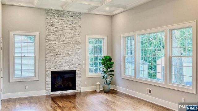 living area featuring coffered ceiling, healthy amount of natural light, wood finished floors, beamed ceiling, and baseboards