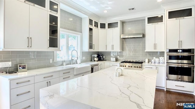 kitchen featuring a sink, appliances with stainless steel finishes, light stone countertops, a center island, and recessed lighting