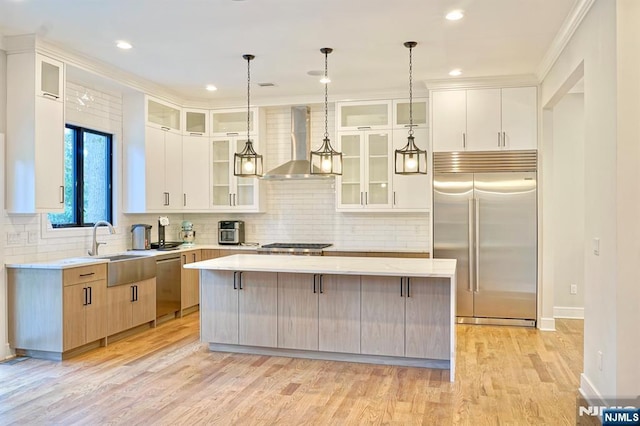 kitchen featuring appliances with stainless steel finishes, wall chimney range hood, a kitchen island, decorative backsplash, and recessed lighting