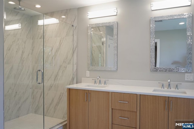 full bath with a marble finish shower, double vanity, and recessed lighting
