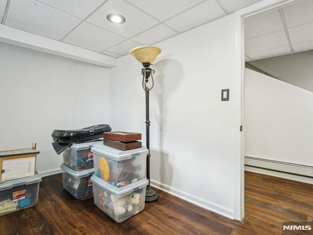 below grade area featuring a drop ceiling, wood finished floors, baseboards, a baseboard radiator, and recessed lighting