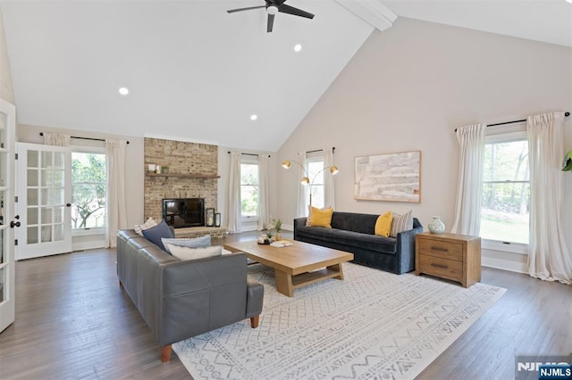 living area featuring high vaulted ceiling, beam ceiling, a ceiling fan, a fireplace, and wood finished floors