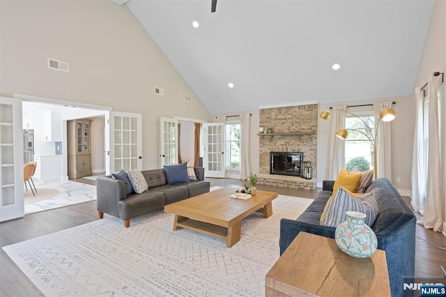 living area featuring high vaulted ceiling, french doors, wood finished floors, baseboards, and a fireplace