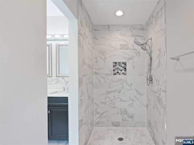 full bath featuring tiled shower, vanity, and recessed lighting