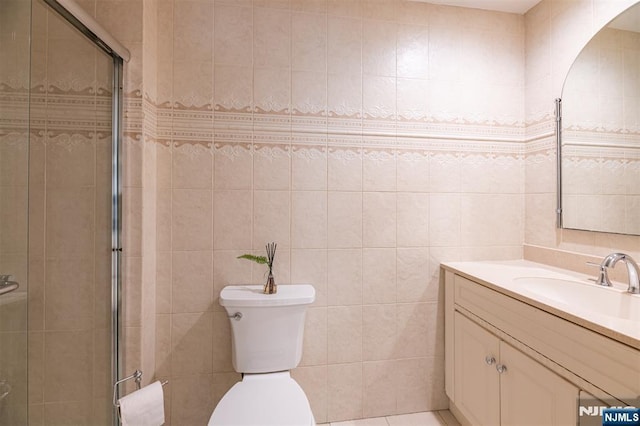 bathroom with tile walls, a stall shower, vanity, and toilet