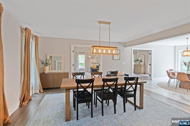 dining space featuring a chandelier, baseboards, and wood finished floors