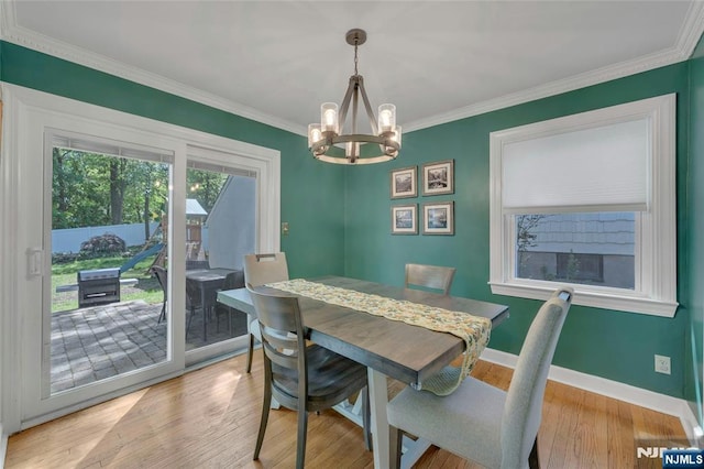 dining area with a chandelier, ornamental molding, baseboards, and light wood-type flooring