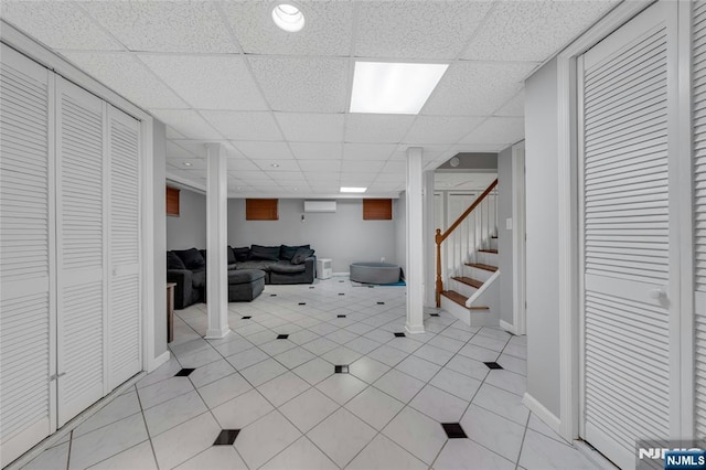 finished basement featuring stairway, a drop ceiling, baseboards, and light tile patterned floors