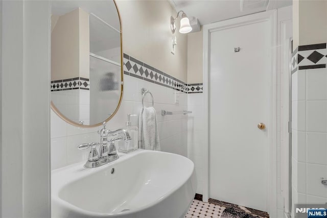 bathroom featuring a sink, tile walls, and a shower with door