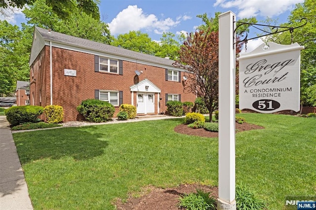 colonial house featuring a front yard, brick siding, and a chimney