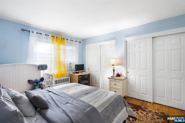 bedroom featuring multiple closets, wood finished floors, and a wainscoted wall