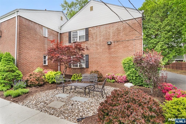 rear view of property with brick siding, a patio area, and fence