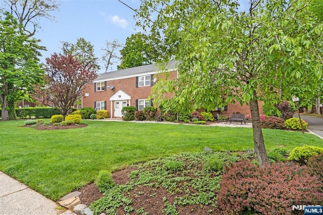 colonial home with a front lawn and brick siding