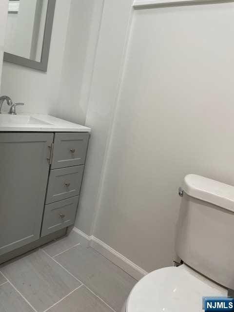 bathroom with tile patterned floors, toilet, vanity, and baseboards
