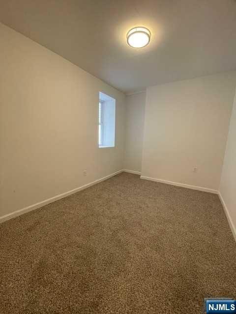 unfurnished room featuring baseboards and dark colored carpet