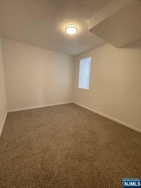 empty room with dark carpet and baseboards