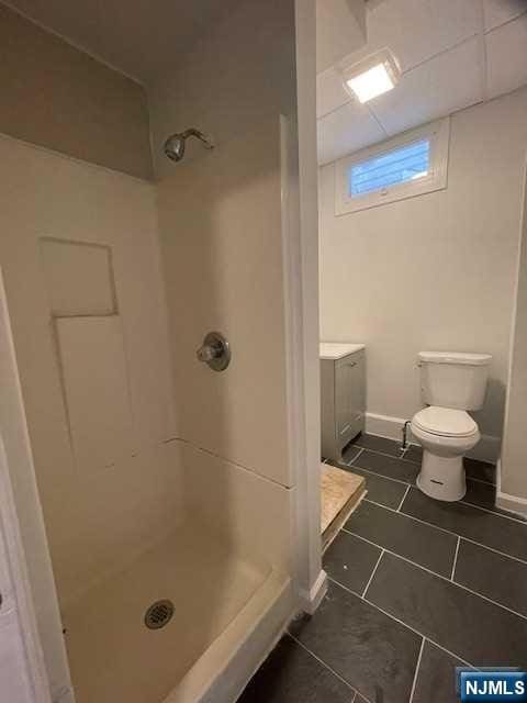full bathroom featuring a stall shower, tile patterned floors, toilet, and vanity