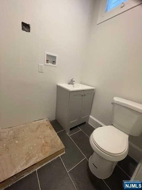 bathroom featuring toilet, tile patterned flooring, vanity, and baseboards