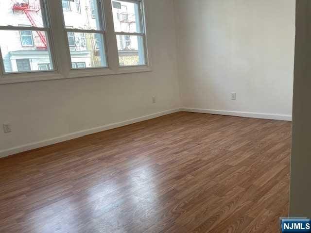 spare room featuring baseboards and dark wood finished floors