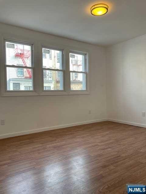 unfurnished room with wood finished floors and baseboards