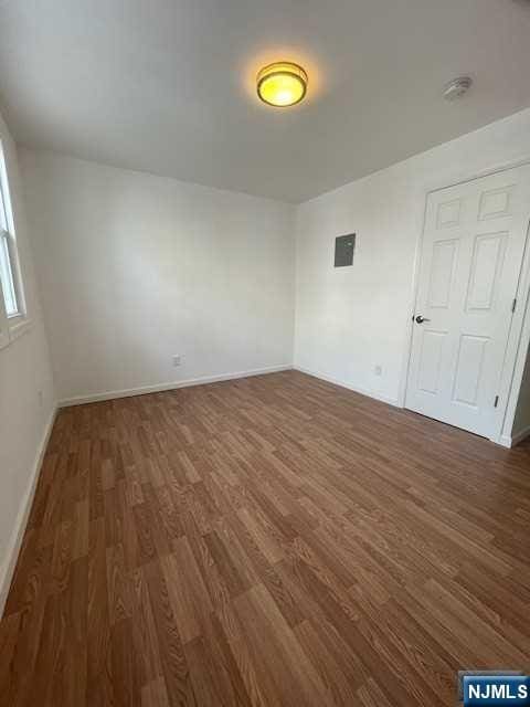 spare room featuring dark wood-style floors, baseboards, and a smoke detector