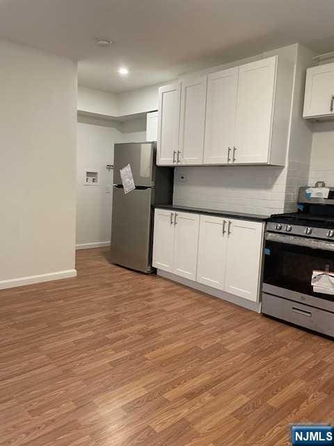 kitchen featuring appliances with stainless steel finishes, light wood-style floors, dark countertops, white cabinets, and recessed lighting