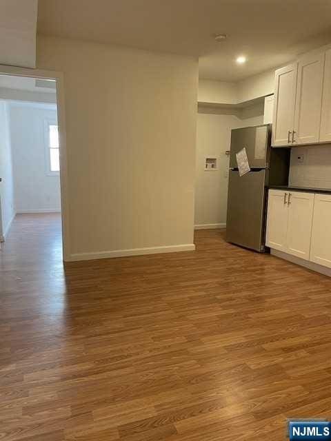 unfurnished living room with baseboards, wood finished floors, and recessed lighting
