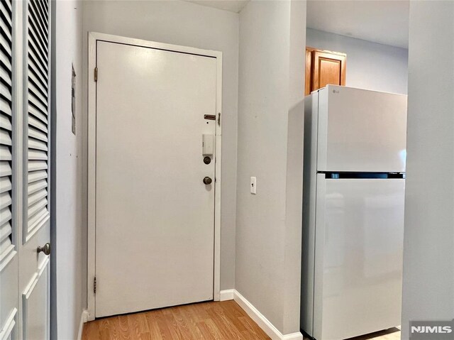 doorway to outside with light wood-type flooring and baseboards