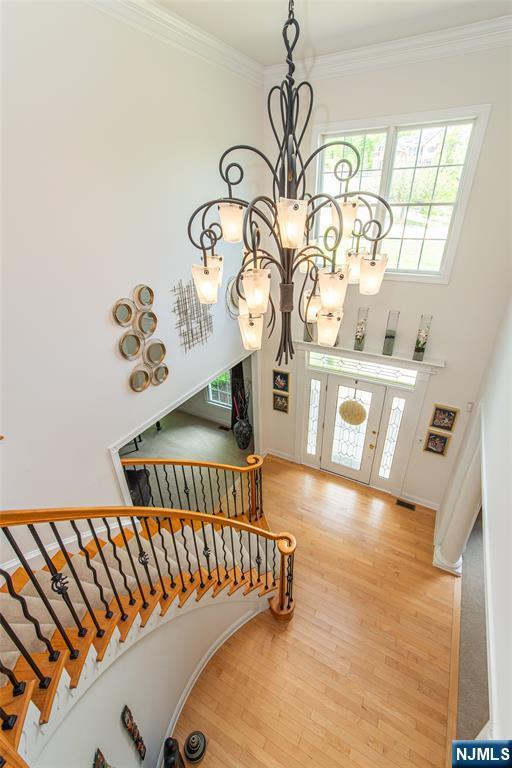 39 Crown View Ct, Sparta, NJ 07871 - stairs featuring a chandelier, wood finished floors, crown molding, a high ceiling, and french doors