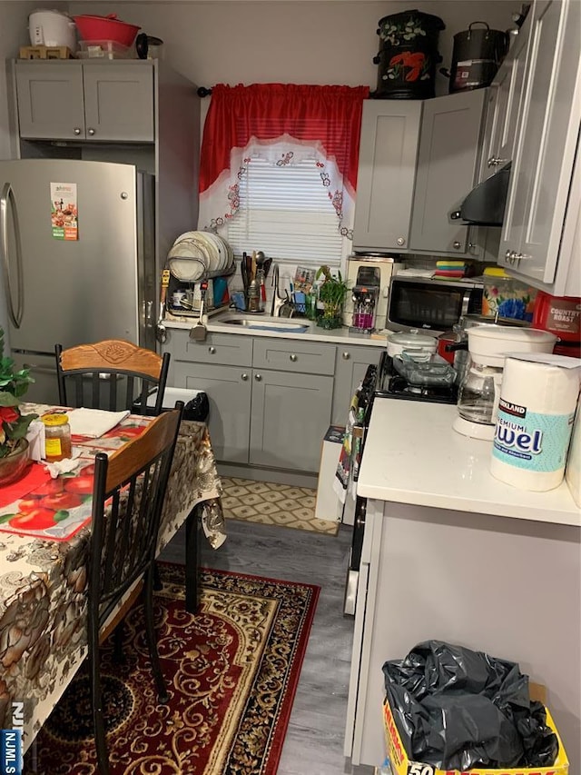154 Butler St, Paterson, NJ 07524 - kitchen with freestanding refrigerator, gray cabinetry, under cabinet range hood, and light countertops