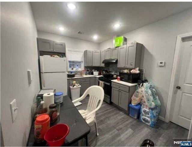 154 Butler St, Paterson, NJ 07524 - kitchen with electric stove, freestanding refrigerator, gray cabinetry, under cabinet range hood, and black microwave