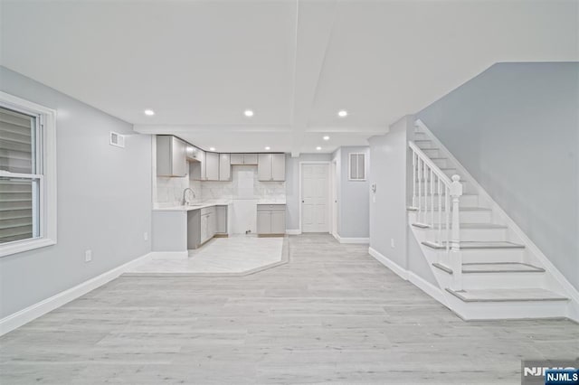 191 Harrison St, Passaic, NJ 07055 - unfurnished living room featuring recessed lighting, a sink, light wood finished floors, stairway, and baseboards