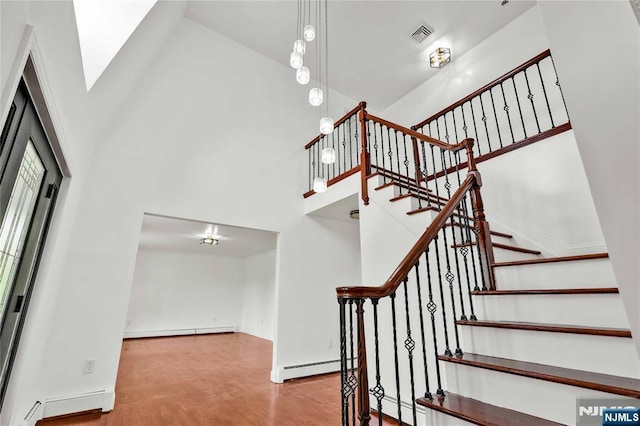 11 Deer Meadow Rd, Warwick, NY 10990 - stairway featuring a baseboard radiator, a towering ceiling, baseboards, and wood finished floors