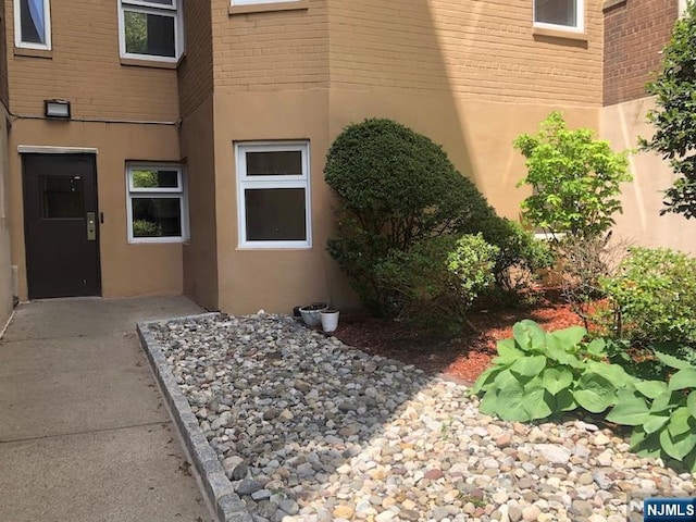 doorway to property featuring stucco siding and brick siding