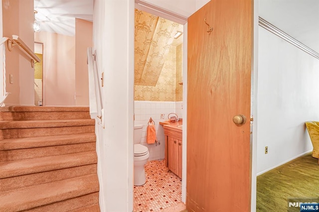 staircase with tile walls and a wainscoted wall