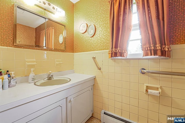 bathroom with tile walls, wallpapered walls, vanity, wainscoting, and baseboard heating