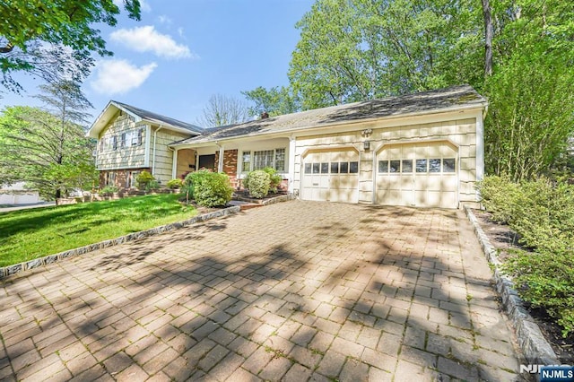 split level home featuring a garage, driveway, and a front lawn