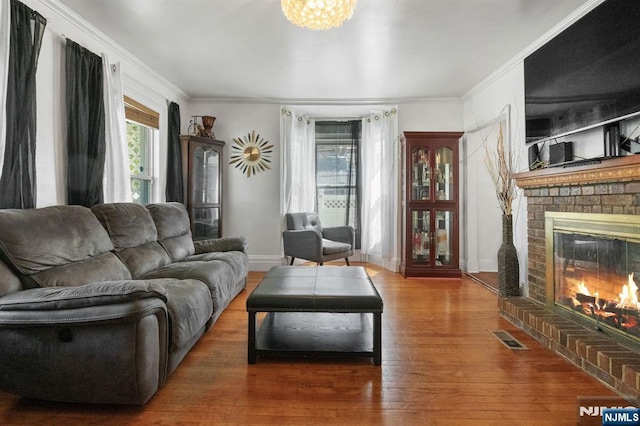 218 Waldo Pl, Englewood, NJ 07631 - living room featuring wood finished floors, crown molding, a brick fireplace, baseboards, and a chandelier