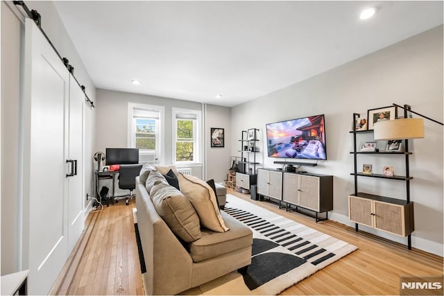 living room featuring a barn door, light wood-style flooring, an office area, recessed lighting, and baseboards