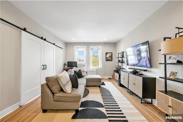 living area featuring a barn door, light wood-style flooring, radiator, baseboards, and recessed lighting