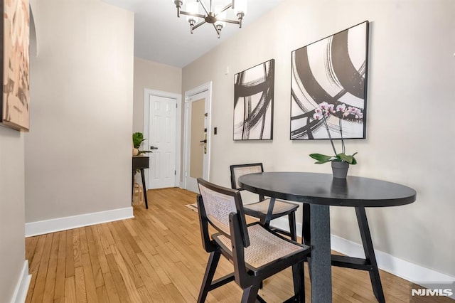 dining room with baseboards, a chandelier, and light wood-style flooring