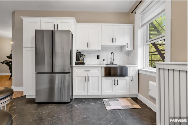kitchen featuring freestanding refrigerator, a sink, plenty of natural light, and light countertops