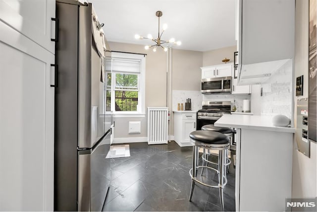kitchen with stainless steel appliances, white cabinets, light countertops, decorative backsplash, and a chandelier