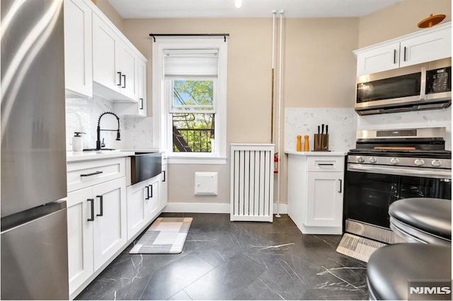 kitchen featuring stainless steel appliances, decorative backsplash, light countertops, and radiator