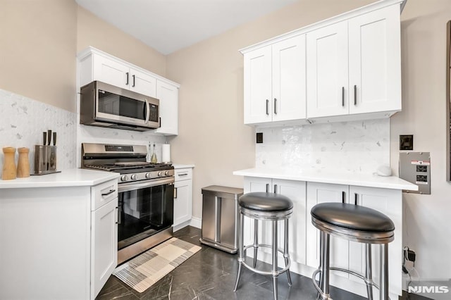 kitchen with stainless steel appliances, decorative backsplash, white cabinetry, and light countertops
