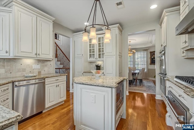 75 Windsor Ln, Ramsey, NJ 07446 - kitchen with stainless steel appliances, a chandelier, a warming drawer, wall chimney range hood, and light wood-style floors