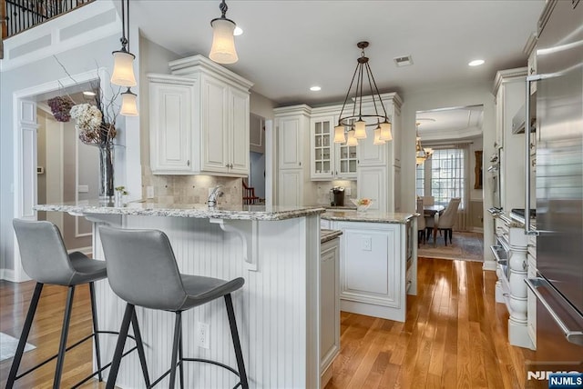 75 Windsor Ln, Ramsey, NJ 07446 - kitchen featuring a peninsula, light wood finished floors, white cabinetry, tasteful backsplash, and glass insert cabinets