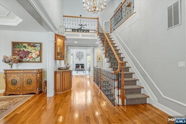 75 Windsor Ln, Ramsey, NJ 07446 - entryway with stairs, light wood finished floors, a lit fireplace, a towering ceiling, and ornamental molding