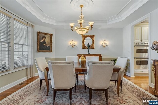 75 Windsor Ln, Ramsey, NJ 07446 - dining area featuring a chandelier, a tray ceiling, light wood-type flooring, baseboards, and ornamental molding